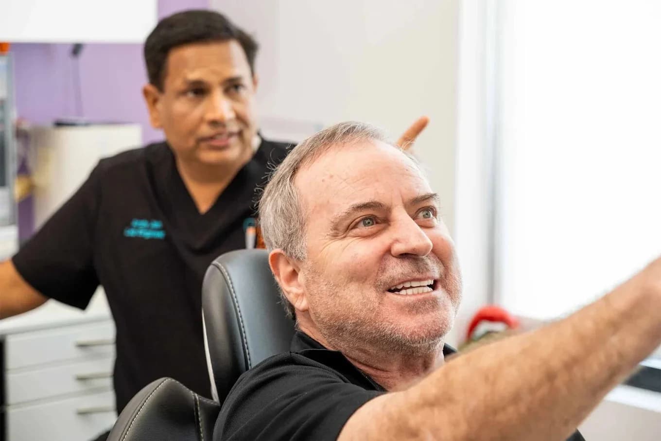 Andy Jain reviewing a restoration with a patient at the lab workstation