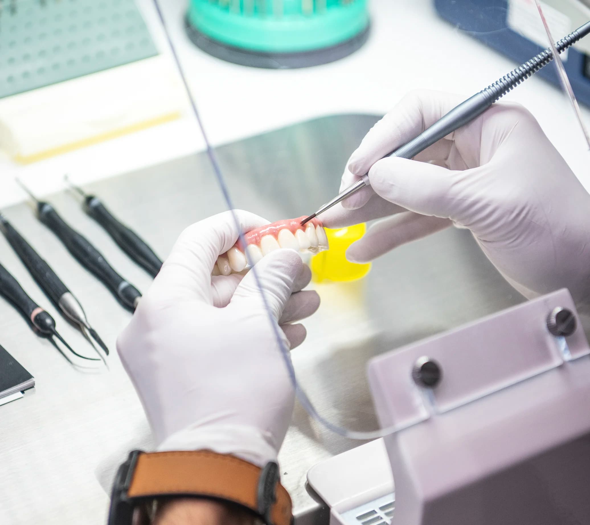 A technician finishing a full-arch implant bridge at the in-house lab bench