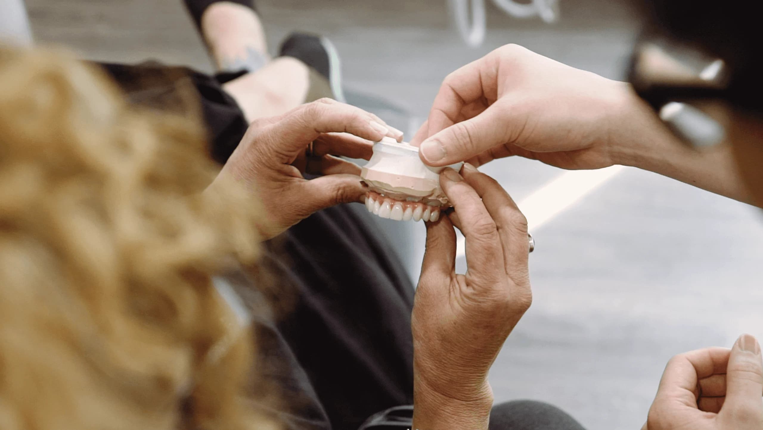 Un clínico mostrando cómo encaja en su modelo una sobredentadura removible sobre implantes