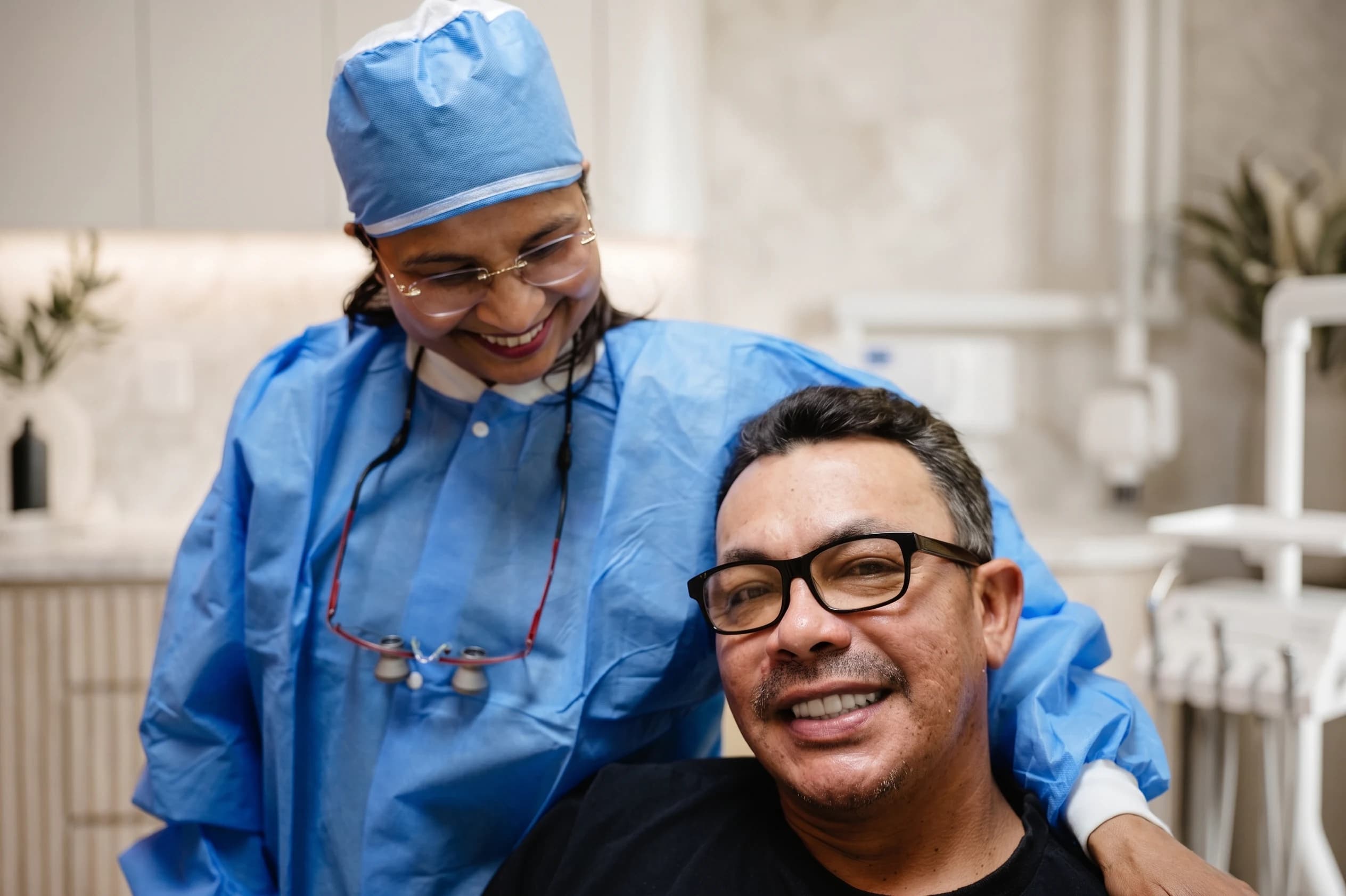 A clinician leaning toward a smiling patient in the treatment chair