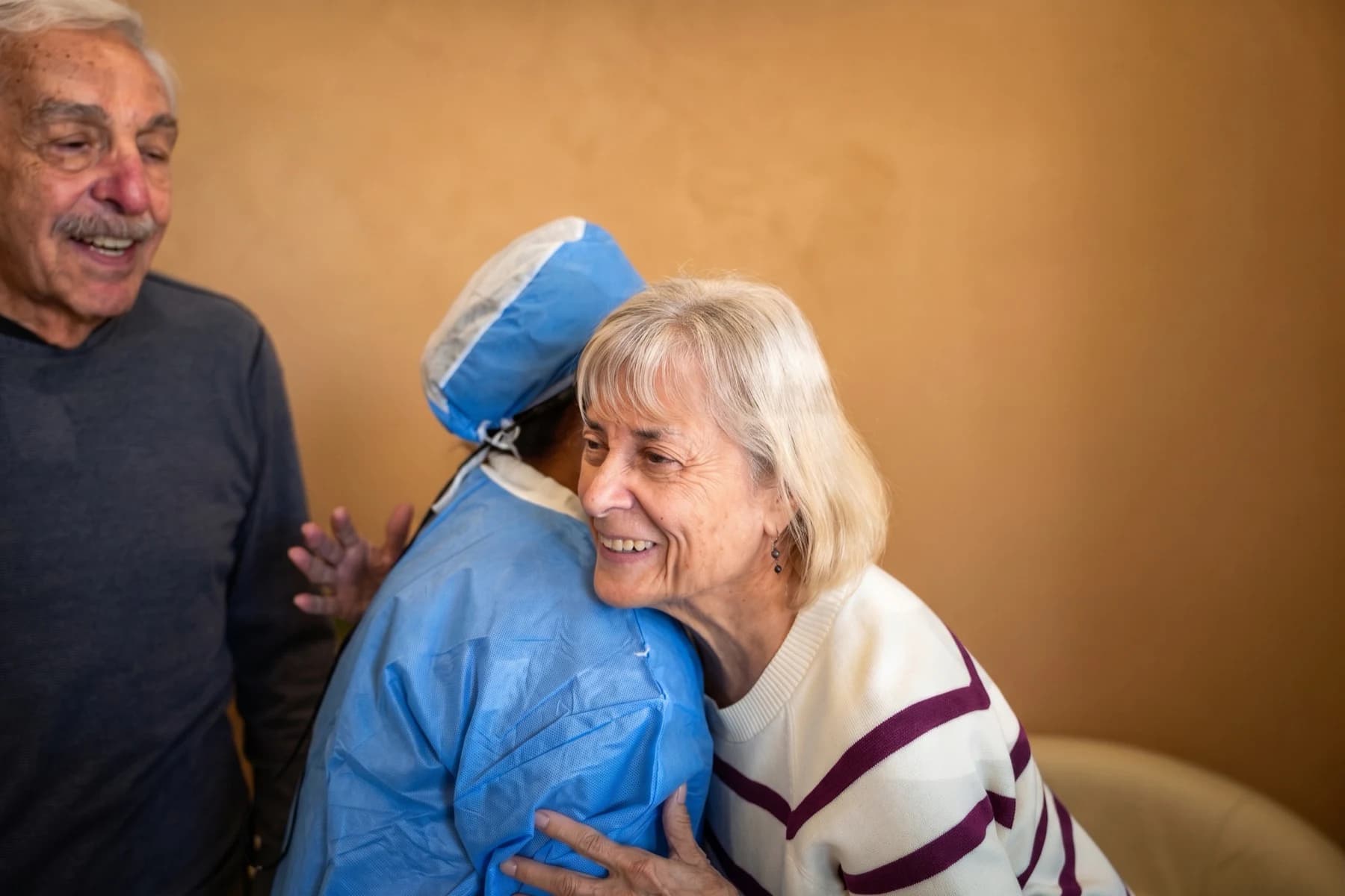 A patient and her husband embracing a surgical assistant