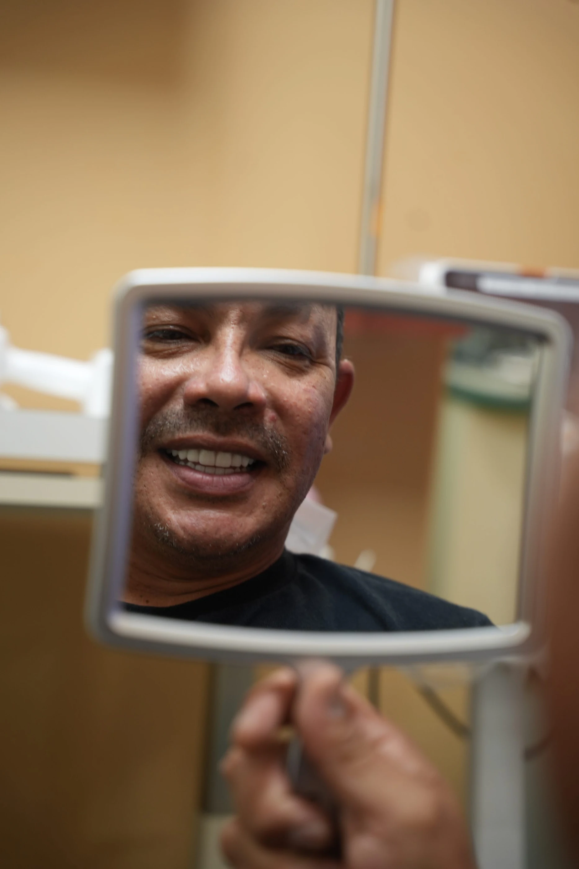 A patient grinning at his reflection in a hand mirror