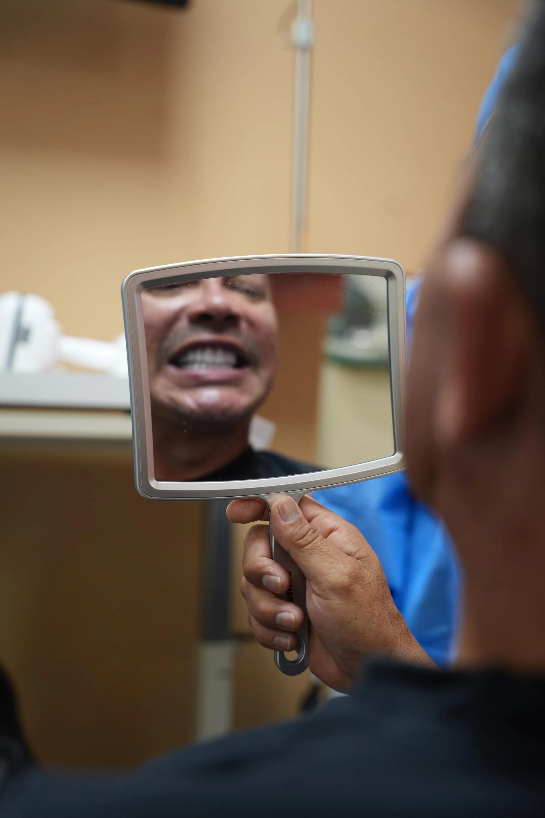 A patient laughing at his reflection in a hand mirror