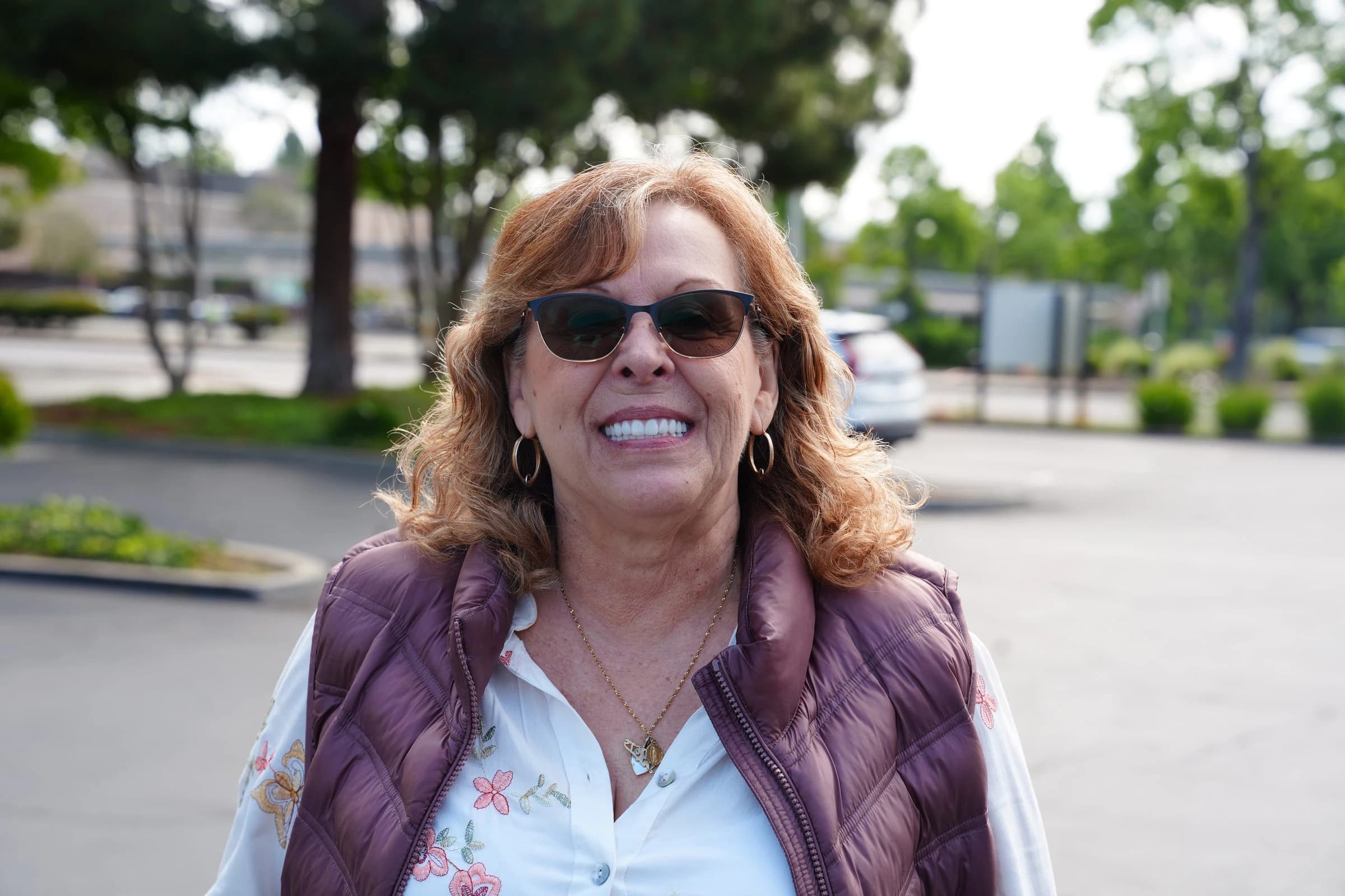 A smiling patient standing outside Center for Implant Dentistry