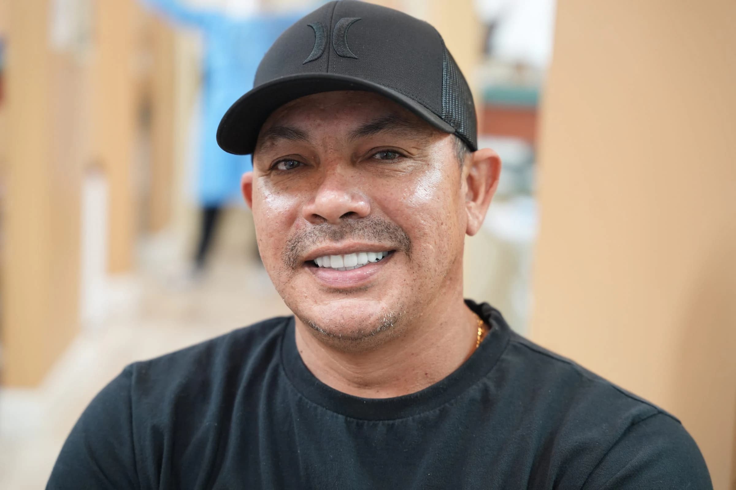 Un paciente sonriendo con una gorra negra en la consulta