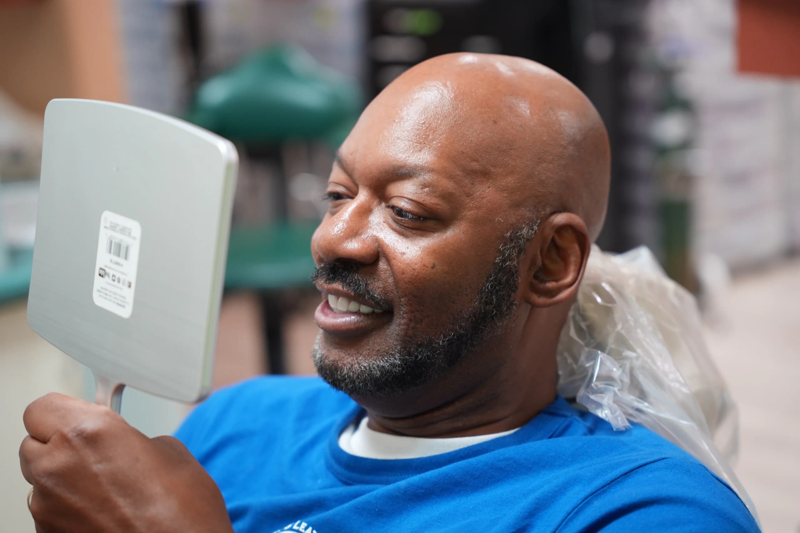 A patient looking at his new smile in a hand mirror